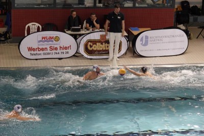 Anschwimmen in der Partie WU Magdeburg gegen OSC Potsdam II. Zusehen sind die WUM Spieler Jan Naveau (weiße Kappe Nr, 5) und der dreifache Torschütze Lukas Schulle (weiße Kappe Nr. 8) sowie der Akteur des OSC Potsdam II Bennet Grandke (schwarze Kappe Nr. 3).